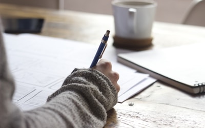 Student working on IELTS preparation with a notebook and laptop on a desk