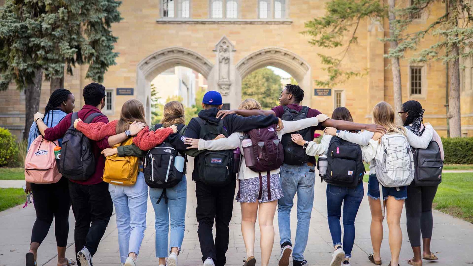 A group of university students standing together outside a campus gate
